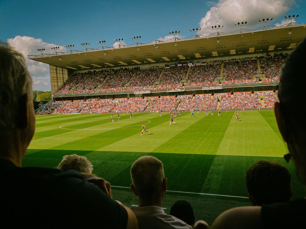 Players playing inside a football stadium on a sunny day.